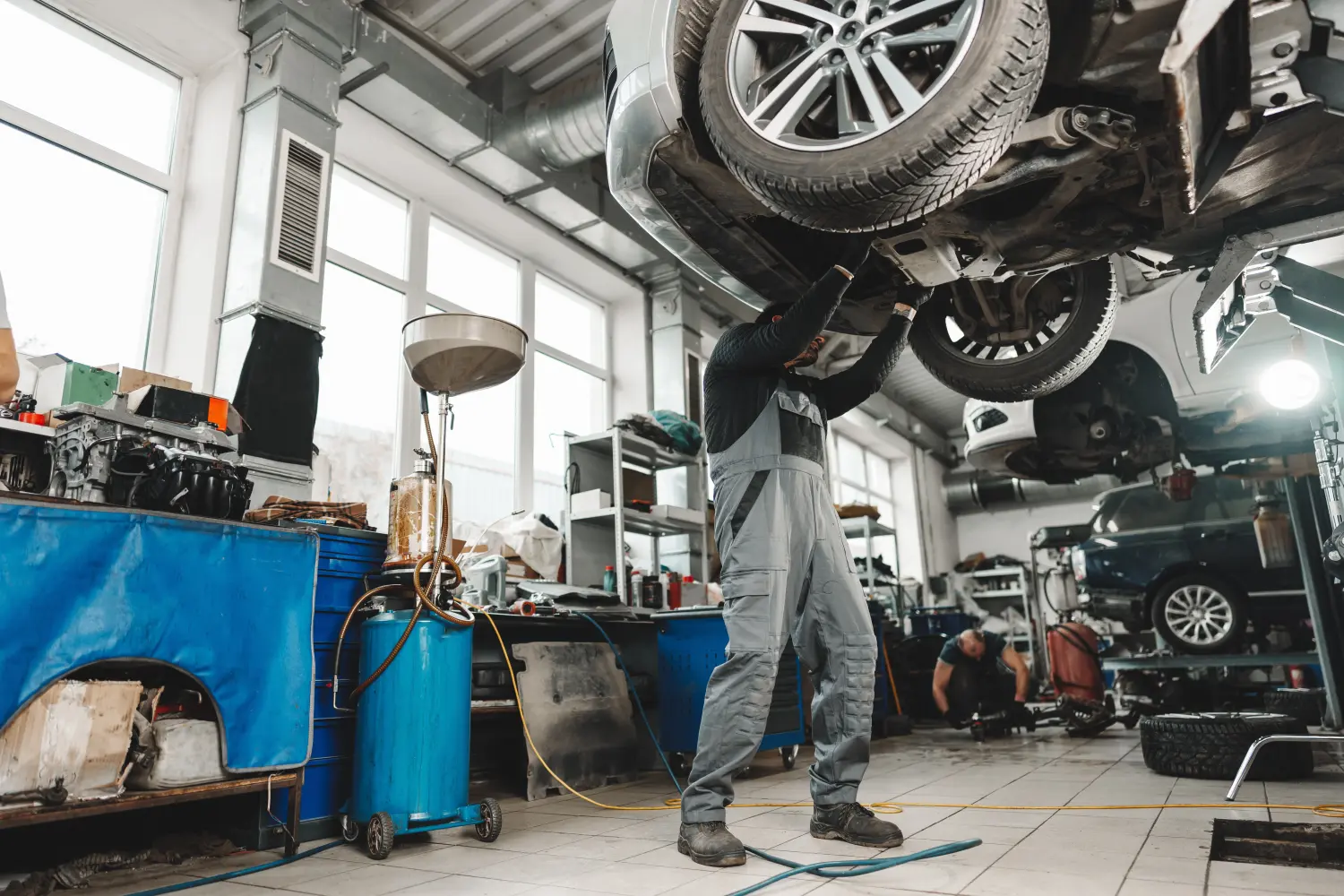 Arbeitermechaniker arbeitet unter Auto in Autowerkstatt